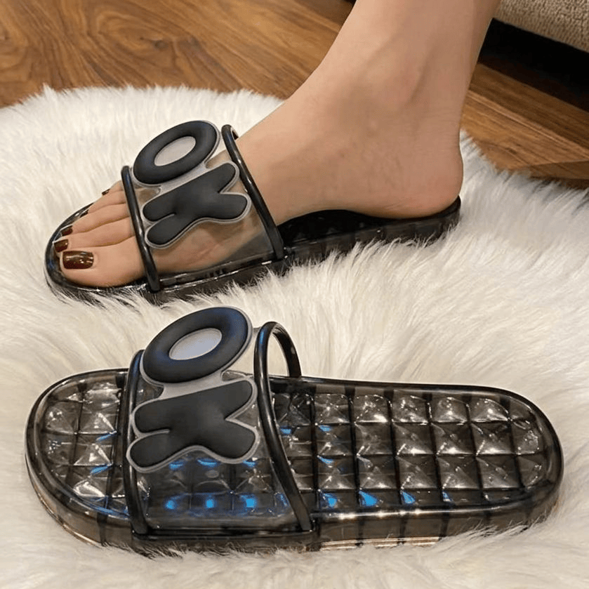 Black jelly sandals with transparent sole on a white rug