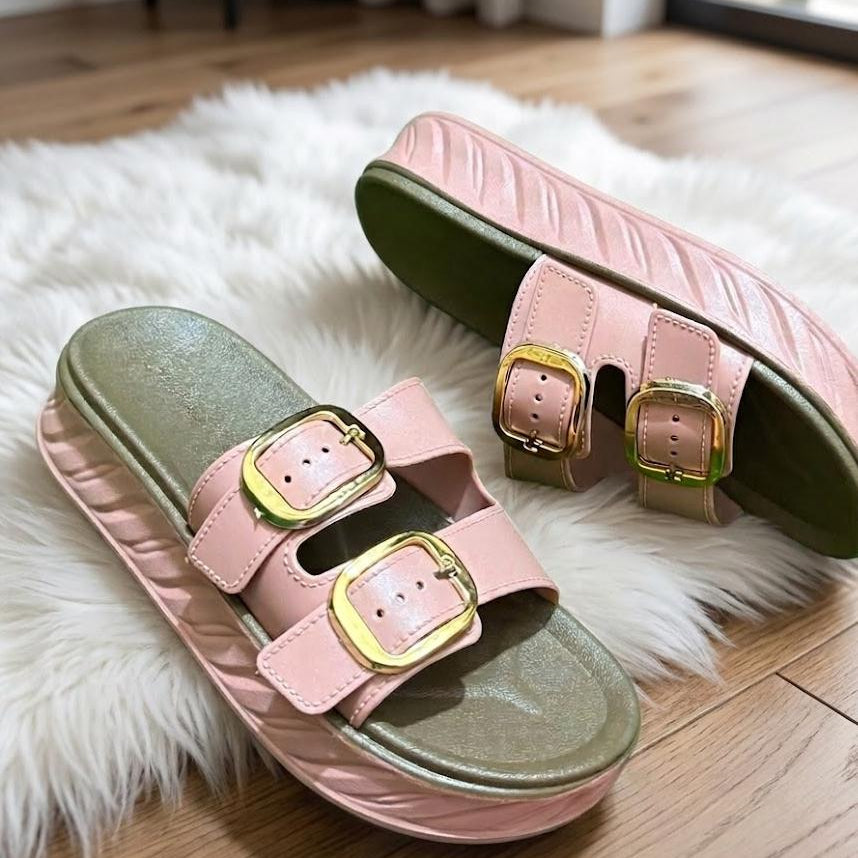 Pink and green sandals with gold buckles on a fluffy white rug.