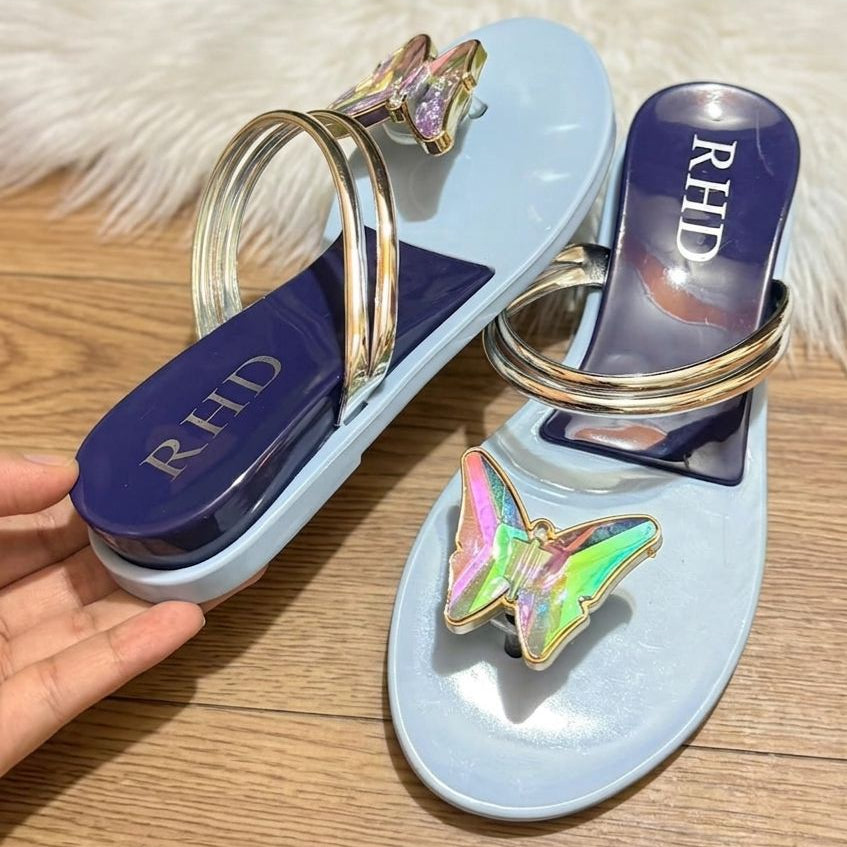 Blue sandal with gold accents and butterfly decorations on a wooden surface.