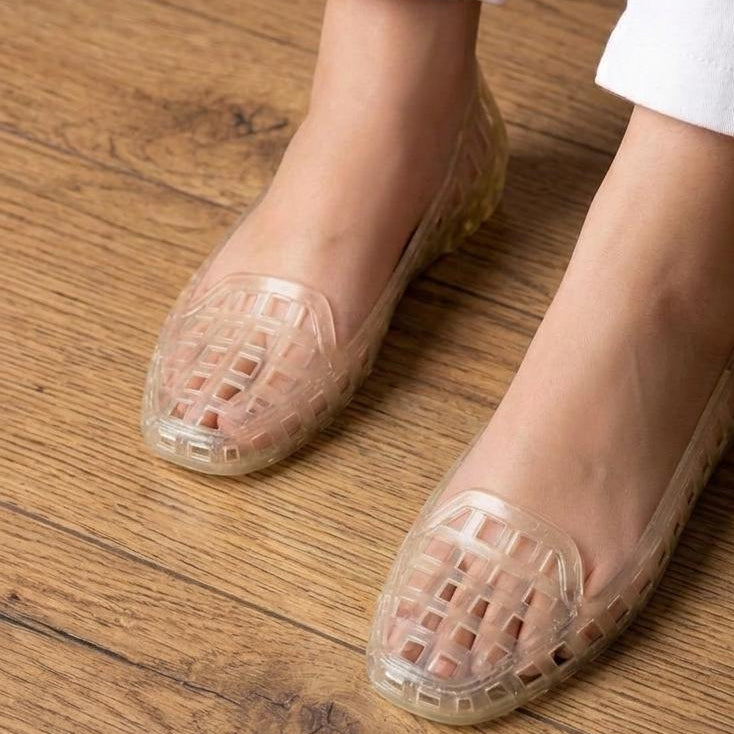Clear jelly shoes worn on a wooden floor