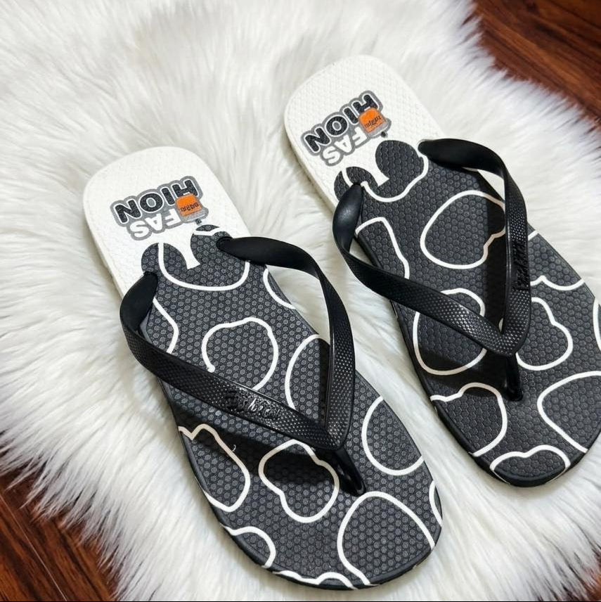 Pair of black and white flip-flops with 'NOAH' branding on a fluffy white surface.