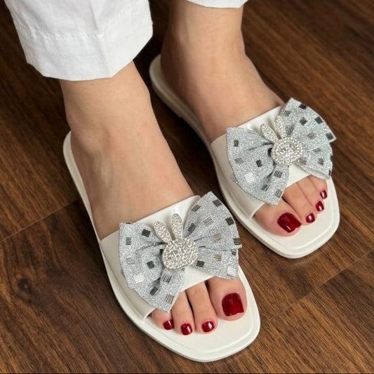 White sandals with decorative flowers worn on a wooden floor, brand 'Fashion Set' visible.