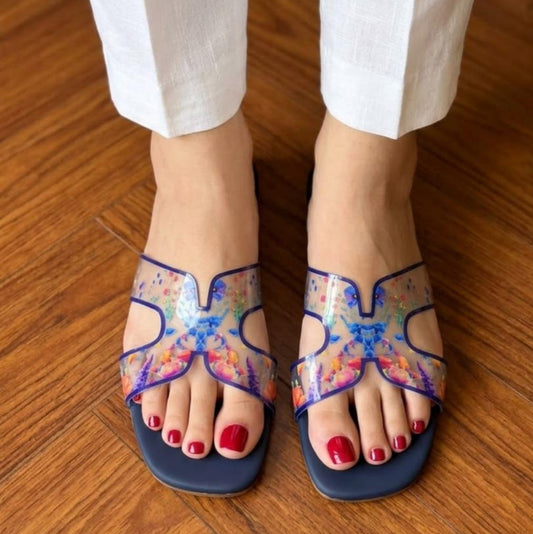 Colorful sandals with butterfly design worn on a wooden floor