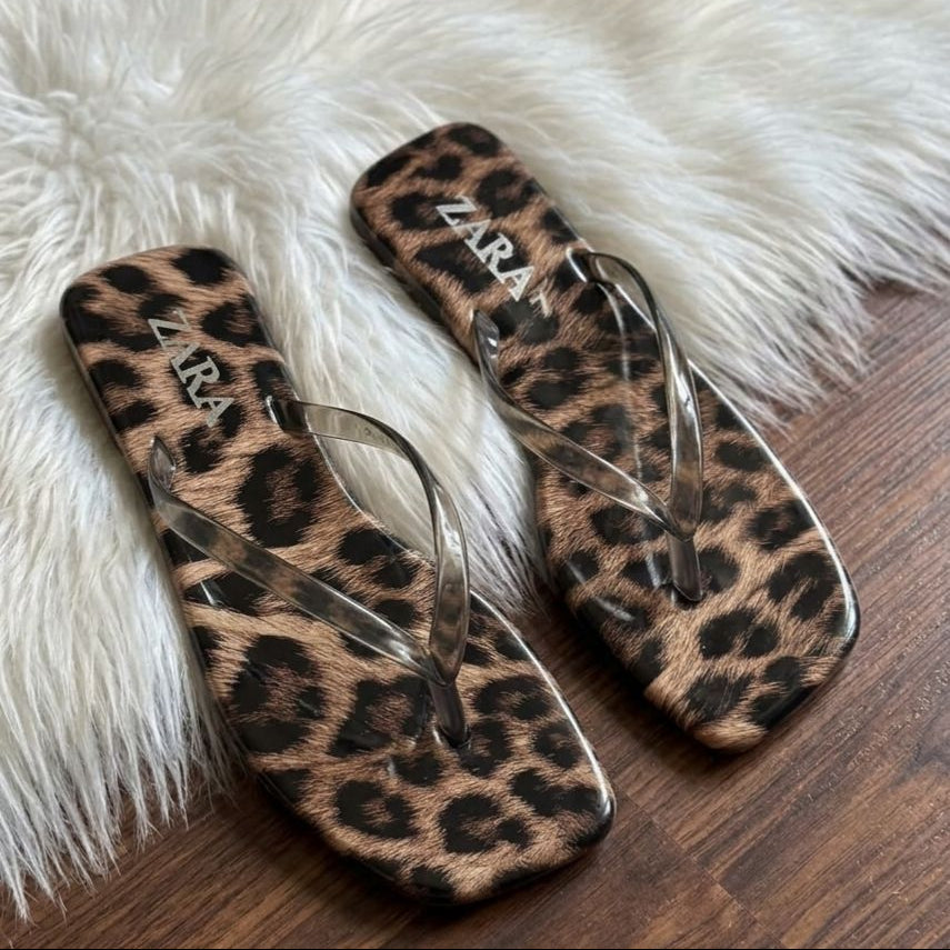 Leopard print sandals with 'Zara' branding on a fluffy white surface.