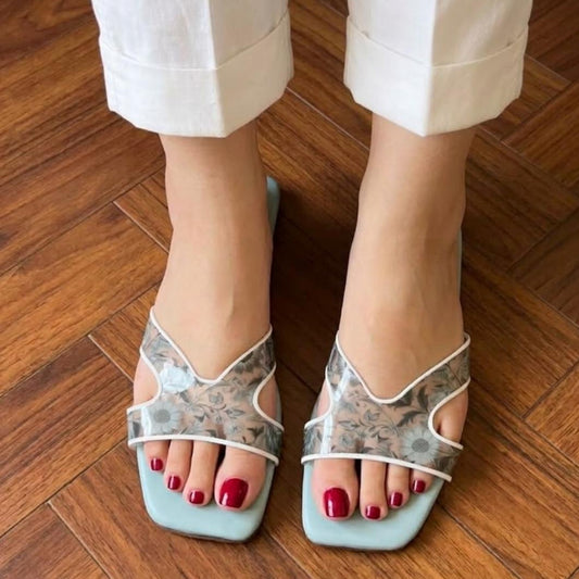Person wearing light blue floral sandals on a wooden floor