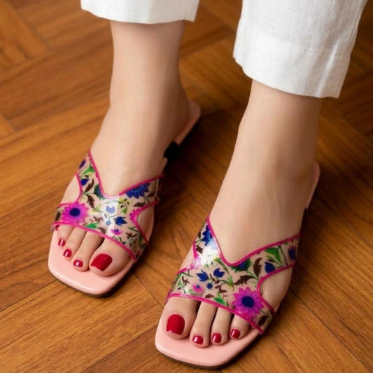 Colorful floral sandals worn on a wooden floor