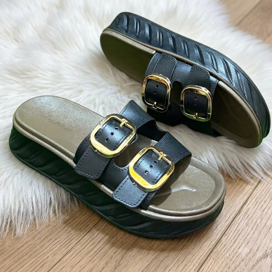 Pair of black sandals with gold buckles on a white fur surface.