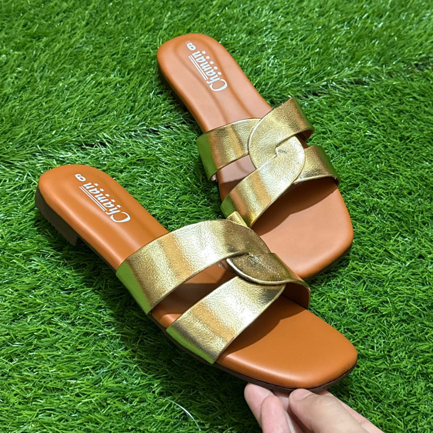 Pair of gold and brown sandals on a grassy background
