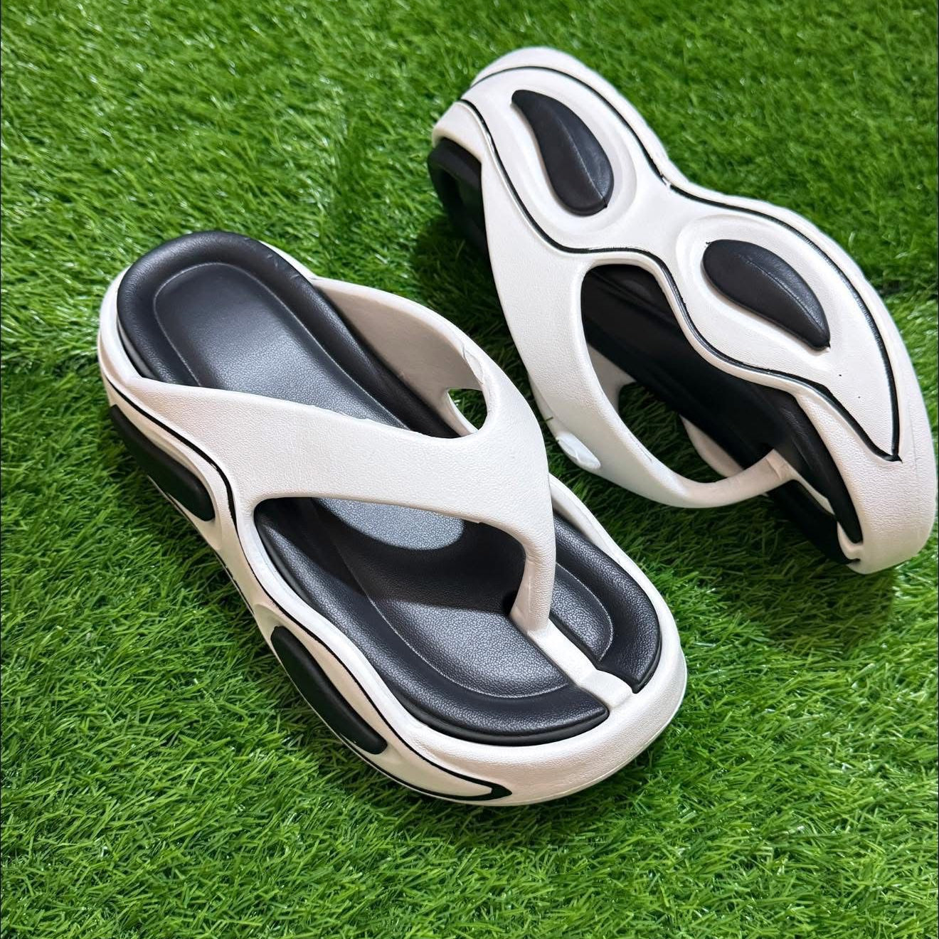 Pair of white and black sandals on a green grass background